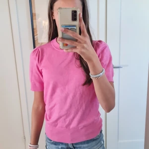 Rosa stickad tröja Saint Tropez XS - Snygg rosa stickad tröja från Saint Tropez. Jat är 170 och tröjan är i storlek XS. Modellen har puffade axlar och korta ärmar, samt ribbade muddar vid hals, ärmslut och nederkant. 