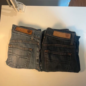 2 par blå jeans från Tiger of Sweden storlek 28/32 - Säljer två par klassiska blå jeans från Tiger of Sweden, modellen är slim fit. Ena paret är ljusblått med slitningar och det andra är mörkblått. Båda har raka ben, fem fickor och snygga detaljer i brunt läder vid linningen. Perfekta för en avslappnad och stilren look. De är ganska små i storleken. Uppskattar att de passar dig som är ca 160-165cm lång. Säljer båda 2 tillsammans för 300 och var för sig 200🤗.Vid frågor så är det bara o skriva! 🤝