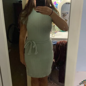 Ljusgrön ribbad kortklänning med knyt - Supersöt ljusgrön ribbad klänning med korta ärmar och rund hals. Medföljer ett matchande bälte att knyta i midjan för extra snygg passform. Materialet är mjukt och stretchigt, perfekt för dig som gillar bekväma och stilrena outfits. Passar dig som vill ha en enkel men trendig look. Materialet är väldigt stretchigt och passar alla kroppstyper, bandet är löst så går att ta bort eller justera.❤️