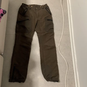 Byxor  från Kayoba Outdoor vargo - Säljer ett par bruna cargopants från Kayoba Outdoor i storlek 46. Byxorna har flera praktiska fickor med dragkedja, förstärkta partier på knän och bak, samt justerbara benslut. Perfekta för uteliv och äventyr. Materialet är slitstarkt och känns  sköna 