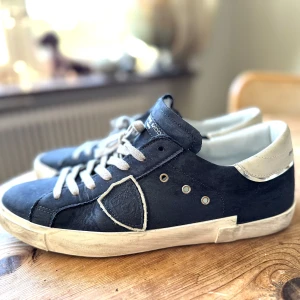 PHILIPPE MODEL BLÅ PRSX LÅGA SNEAKERS - Levela upp din stil med Philippe Model PRSX sneakers. Blå nubuck med coola detaljer, slitna kanter och en fresh kontrast-häl. Vintage vibe möter modern look. Skön passform med skuminnersula och grym komfort. Perfekt för dig som vill sticka ut. Nypris omkring 3600:- se ex: https://www.miinto.se/p-bla-prsx-laga-sneakers-ebfa650d-4aeb-49d1-aa17-d437dcc11aa1?utm_source=google&utm_medium=cpc&utm_campaign=SE%7CShopping%7CShoes&gad_source=1&gad_campaignid=22114305991&gclid=Cj0KCQjw5JXFBhCrARIsAL1ckPt