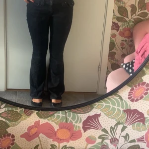 svarta true religion jeans  - Säljer ett par svarta true religion jeans flare och låg midja. Snygga detaljer med knappar på bakfickorna. 