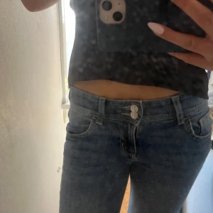 Lågmidjade jeans - Säljer ett par slutsålda bootcut jeans från H&M med låg midja. Jeansen har dubbla knappar fram, snygga bakfickor med lock och knappar. De har ett litet slitage längst ner på byxorna, men övrigt är de i bra skick.