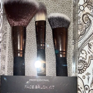 Professionellt Face Brush Kit - Säljer ett professionellt Face Brush Kit med tre borstar: en stor puderborste, en foundationborste och en skulpteringsborste. Borstarna har mjuka syntetiska strån i brunt och vitt, eleganta roséguldfärgade detaljer och svarta handtag. Perfekt för att skapa en flawless bas och contour.