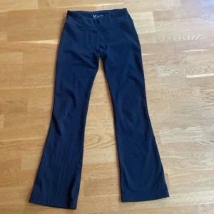 Svarta bootcut träningsbyxor SOC - Svarta träningsbyxor från SOC med bootcut-ben och hög midja. Byxorna är gjorda i ett stretchigt syntetmaterial med TCS Airflow-teknologi som håller dig torr och bekväm. Perfekta för gymmet eller danspasset.