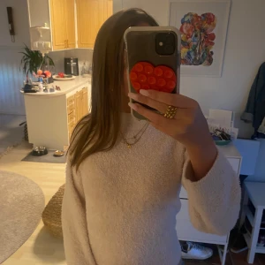 Ljus rosa  fluffig tröja från H&M - Supermjuk och fluffig beige tröja från H&M med långärmade ärmar och relaxed passform. Perfekt för dig som gillar mysiga vibes och vill ha något riktigt skönt att bära. Materialet är syntet och ger en gosig känsla hela dagen.