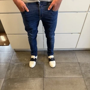 Replay mörkblå skinny jeans herr - Säljer ett par mörkblå jeans från Replay i modellen skinny fit. Jeansen har klassisk femficksdesign, snygga sömmar på bakfickorna och smal passform hela vägen ner. Perfekta för dig som gillar en tajt look och vill ha jeans med lite stretch.