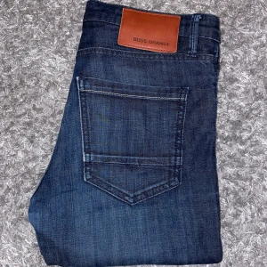 Boss Orange mörkblå slim jeans - Snygga mörkblå jeans från Boss Orange, modell Orange 71 med slim fit. Klassisk femficksdesign, läderpatch med logga bak och diskreta kontrastsömmar. Jeansen är tillverkade i mjukt denimtyg som sitter tajt men bekvämt.