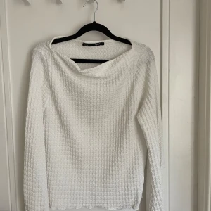 Vit långärmad tröja med vågigt mönster - Säljwr en tröja från lager 157.  Tröjan har ett unikt vågigt mönster över hela ytan och en lite bredare halsringning. Materialet känns mjukt och har en lätt struktur som gör den extra intressant. Perfekt för dig som gillar stilrena och coola detaljer.
