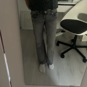 Grå bootcut jeans från Gina Tricot - Säljer ett par grå jeans från Gina Tricot i storlek 152. Modellen har bootcut-ben, klassisk femficksdesign och snygga detaljer med knappar på bakfickorna. Jeansen har dragkedja och knapp framtill och är tillverkade i jeansmaterial.