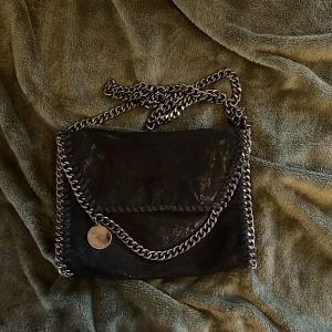 Stella McCartney liknande väska - Svart Stella McCartney liknande väska med silverdetaljer, använd en eller två gånger så nästan nyskick. Lätt att stylea och passar mycket bra som accessoar till de flesta outfits. Perfekt om man vill ha en lite mindre väska till t.ex skolan💕köpare står för frakten