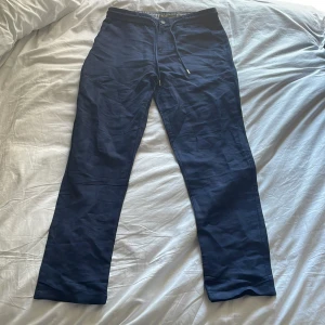 Mörkblå linnebyxor red jack - Snygga mörkblå byxor från Red Jack med dragsko i midjan och raka ben. Byxorna har ett klassiskt snitt och är perfekta för en avslappnad stil. Insidan av midjan har ett randigt tyg för extra detalj. Storlek L/44. Säljer dessa då de tyvärr inte passade i storlek för mig. 