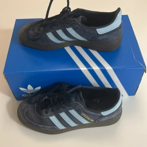 Adidas Spezial sneakers marinblå mocka - Adidas Spezial sneakers i marinblå mocka med ljusblå detaljer och klassiska tre ränder på sidan. Snygg retrostil med svart sula och snörning. Perfekt för dig som gillar streetwear och vill sticka ut med en ikonisk modell.