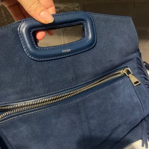  Maje väska blå - Snygg blå axelväska från Maje i mocka med fransar på sidorna och  handtag upptill, kommer även till ett längre band. Väskan har guldfärgad dragkedja och justerbar axelrem. I superfint skick! 