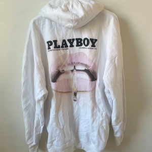 Vit hoodie från Playboy x Missguided - Hoodie från Missguided x Playboy. Storlek 6(XS) men är extremt oversize, stor och mysig på mig som har storlek S. Stort Playboy tryck på ryggen samt liten Playboy text på framsidan. Använt men bra skick, lite små noppror utspritt, var god se sista bilden. Jag har massor av artiklar till salu! Köp flera och få rabatt!Säljer en vit hoodie från Playboy x Missguided med tryck av läppar och texten PLAYBOY på ryggen. Framtill finns en liten lila logga. Hoodien har huva, känguruficka och långa ärmar. 
