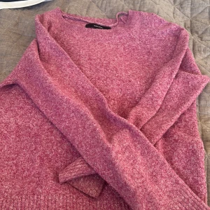 Rosa stickad tröja från veramoda - Mysig rosa stickad tröja från veramoda med rund hals och långa ärmar. Tröjan har en mjuk och lite melerad yta som ger en chill vibe. Perfekt att slänga på sig när det är kallt ute. Passar dig som gillar enkel och stilren design.