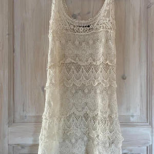 Vit spetsklänning från Gina Tricot - Supersöt vit stickad vit klänning från Gina Tricot i storlek XS. Klänningen har flera lager med detaljerad spets och ett romantiskt mönster. Perfekt för sommarens alla tillfällen!