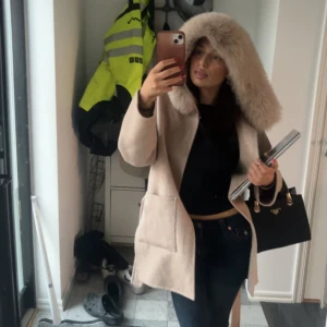  pälsjacka med huva från FUR STOCKHOLM  - Säljer nu min väl använda pälskappa från fur Stockholm i färgen camel. Den är köpt för 2000kr från fur Stockholms hemsida den är i fint skick men med små skador. En knapp har gått av vid pälsen samt lappen är påväg av. Men annars är den i fint skick. Priset kan diskuteras hör av vid intresse eller fler bilder 💕💕