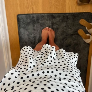 Vit prickig omlottkjol med volang - Superfin kort omlottkjol i vitt med svarta prickar och volangkant. Kjolen har en lätt och flowy känsla, perfekt för varma dagar. Sitter snyggt i midjan och är inte för kort. 