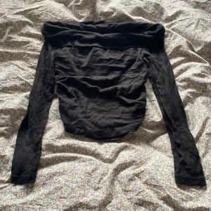 Svart offshoulder långärmad topp - Snygg svart offshoulder topp med långa ärmar som ger en cool, trendig look. Perfekt att styla med jeans eller kjol för en stilren outfit.