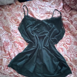 Mörkgrön spetslinne med tunna band - Supersöt mörkgrönt linne med tunna axelband och v-ringad spets upptill. Se på skriv privat!