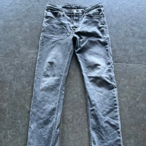Ljusgråa Levis jeans barn storlek - Snygga grå Levis 511 jeans med klassisk femficksdesign och raka ben. Jeansen har en stilren tvättad look och är tillverkade i mjukt bomullsmaterial med en touch av stretch för extra komfort. Den bruna designlappen på baksidan av ena fickan har gått bort men annars är dem hela och i bra skick.