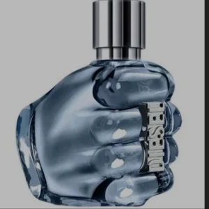 Diesel Only The Brave parfym - Cool parfymflaska från Diesel formad som en knytnäve i blått glas med silvrig metallkork och Diesel-logga på sidan. Flaskan har en unik och edgy design som verkligen sticker ut i badrumshyllan.