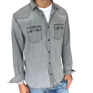 Grå jeansskjorta med knappar - Snygg grå jeansskjorta med svarta knappar och två bröstfickor med lock och knappdetaljer. Skjortan har lång ärm och klassisk krage, perfekt att bära öppen över en t-shirt för en avslappnad look. Storlek L men passar M 