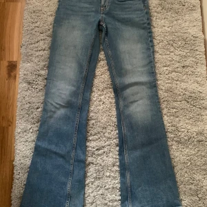Blå bootcut jeans med utsvängda ben - Säljer ett par klassiska blå jeans med bootcut-modell och utsvängda ben. Jeansen har en ljus tvätt och raka bakfickor. Perfekta för dig som gillar retrovibbar och vill ha en snygg siluett. Materialet är jeans och färgen är ljusblå.