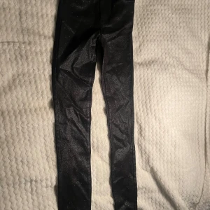 Svarta glittriga jeans från Vila XS - Snygga svarta jeans från Vila i super slim fit med glittrig finish. Byxorna har regular waist och sitter tajt hela vägen ner. Perfekta för dig som vill sticka ut med lite extra glitter i vardagen. Modellen heter Vicommit RW Glitter Coat Jeans. Nypris 500kr