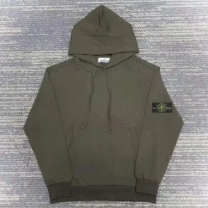 Mörkgrön Stone Island hoodie  - Säljer en snygg mörkgrön hoodie från Stone Island med klassisk logotyp på ärmen. Tröjan har huva med snörning, stor magficka och ribbade muddar. Perfekt för dig som gillar streetwear och vill ha något stilrent och bekvämt.