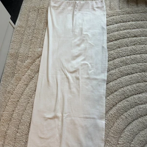 Vit långkjol från Bershka - Enkel och stilren vit långkjol från Bershka i mjukt bomullsmaterial. Kjolen har rak passform och resår i midjan för en bekväm känsla. Perfekt att styla med sneakers eller sandaler för en clean look.