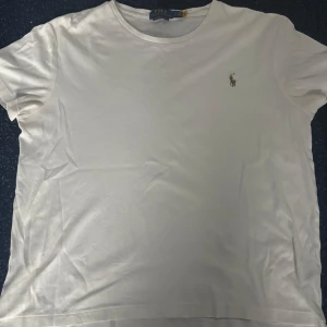 Vit t-shirt Polo Ralph Lauren slim fit - Vit t-shirt från Polo Ralph Lauren i slim fit-modell. Klassisk design med rund hals och korta ärmar, tillverkad i mjuk bomull. Diskret broderad logga på bröstet ger en clean och stilren vibe. Perfekt för dig som gillar enkel och snygg streetstil.