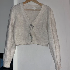 Beige ribbad kofta med snörning - Superfin croppad beige kofta med ribbad struktur och snygga snörningsdetaljer framtill. V-ringad och långärmad, perfekt att slänga över en topp för en chill men ändå trendig look.