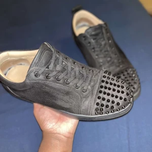 Christian Louboutin svarta sneakers med nitar - Svarta sneakers i mocka från Christian Louboutin med ikoniska röda sulor och svarta nitar på tån. Skorna har snörning och rund tå, samt lyxig beige insida i skinn. OBS! Saknar två nitar på vänstra. (Pris kan diskuteras)