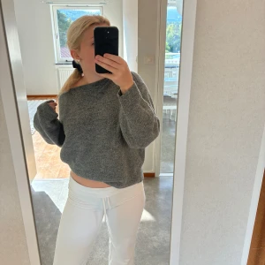 Grå stickad tröja med loose fit - Mysig grå stickad tröja med loose passform och långa ärmar. Perfekt för kyliga dagar och enkel att matcha med både jeans och mjukisbyxor. Tröjan har en avslappnad look och är superbekväm att bära.