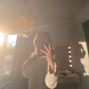 Vit stickad långärmad klänning - Säljer en vit stickad klänning med lång ärm och snyggt vågiga kanter vid ärmslut och nederkant. Tröjan har en rundad, bred urringning och är figurnära i modellen. Använd 1 gång