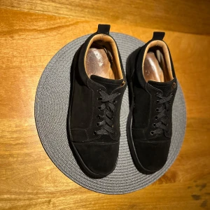 Ytterst använda Loubs - Stilrena svarta sneakers i mocka med klassisk snörning och rund tå. Skorna har en unik röd sula med mönstrad design och insida i ljust skinn. Perfekta för dig som vill ha en clean look med en cool detalj under foten. Har slit på vissa ställen och därav ett billigt pris då jag inte längre vill ha dom och orkar/har inte kunskap att fixa till dom….         Storlek 43 men passar för något större storlek. Kom gärna med frågor eller funderingar jag är alltid ärlig och rak.