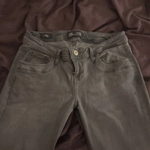 Gråa ultra low jeans från LTB med raka/flare ben - Snygga grå jeans från LTB med klassisk femficksdesign och raka ben. Jeansen har låg midja och subtila detaljer på bakfickorna. Tillverkade i mjuk bomullsblandning som ger en skön passform. Perfekta för en avslappnad och stilren look.