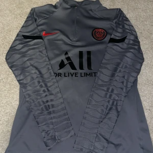 Mörkgrå PSG tröja - Snygg mörkgrå långärmad PSG-tröja från Nike med svarta och röda detaljer. 