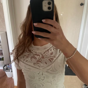 Vit spetsblus från Vila - Supersöt vit spetsblus från Vila i storlek S. Blusen har korta ärmar, hög hals och ett detaljerat spetsmönster över hela plagget. Snygg v-ringad detalj framtill! Använd få gånger🤍🤍