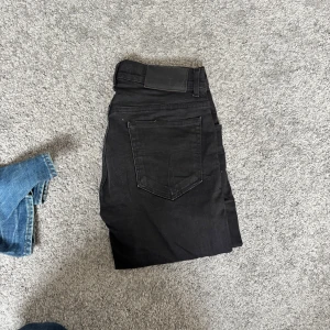 Svarta slim jeans tiger of Sweden 30/32 - Svarta jeans från tiger of Sweden i slim fit-modell. Snyggt klassisk femficksdesign med svarta sömmar och knappgylf. Jeansen har en rak och smal siluett som sitter tajt längs benen. Perfekt för dig som gillar en stilren look med lite edge.