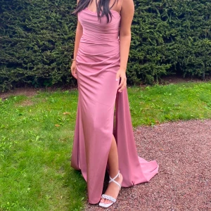 Rosa balklänning  - Elegant rosa långklänning med axelbandslös design och smickrande drapering. Klänningen har en slits framtill! Superfin och passar till bal, eller festligare tillställningar. Klänningen har användes 1 gång på ett bröllop och Inköpspriset var 5000kr (hos dressroom linne). Jag är villig till att diskutera priset!! 🩷