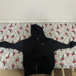Svart hoodie från Polo Ralph Lauren - Säljer en stilren svart hoodie från Polo Ralph Lauren med dragkedja och det klassiska broderade logotypen på bröstet. Perfekt för en avslappnad look. 🖤