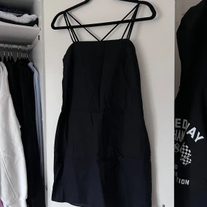 Svart linneklänning med smala axelband (NY) - Snygg svart linneklänning från H&M med smala korsade axelband och dragkedja på sidan. Perfekt för en stilren look. Klänningen har en enkel och elegant design som passar till många tillfällen 🖤 Önskar du exakta mått? Tveka inte att höra av dig!