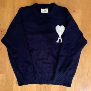 Mörkblå stickad tröja Ami Paris - Säljer en snygg mörkblå stickad tröja från Ami Paris som passar perfekt nu till kvällarna på våren/sommaren. Inga synliga skador och kom privat för detaljbilder på t.ex logga. Storlek Medium. Pris 1800, kan diskuteras.