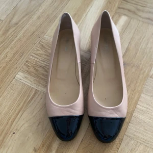 Beige och svarta pumps - Snygga pumps i beige med svart lackad tå. De har en låg klack och en elegant design som passar perfekt för en stilren look.