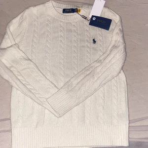 Vit stickad tröja från Polo Ralph Lauren - Säljer en stilren vit stickad tröja från Polo Ralph Lauren med kabelstickat mönster. Fick den i födelsedags present men passar inte mig