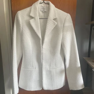 Vit kavaj från Josefine HJ x NA-KD - Snygg vit kavaj från Josefine HJ x NA-KD i ett strukturerat tyg. Kavajen har en klassisk krage och stängs med hakar framtill. Toppskick då den tyvärr aldrig kommit till användning. Nypris är kring 1000 kr. Fler bilder skickas vid intresse!