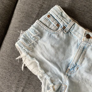 Ljusblå jeansshorts - Snygga ljusa jeansshorts från GAP med slitna detaljer och fransiga kanter. Perfekta för en avslappnad stil. De har en klassisk femficksdesign och knappgylf. Passar perfekt för varma sommardagar.